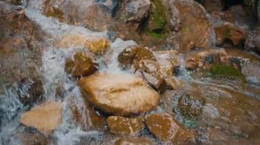 Turuncu kayalıklardaki dağ deresinde akan suyun yavaş çekim rahatlama arka planı. Turist yolunda sakin bir manzara. Nehir kenarından su sıçrıyor.. 