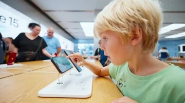 Çocuk, Apple Store 'da yepyeni iPhone 15 akıllı telefondan video oyunu oynuyor. İnsanlar yeni teknolojik cihazlar almaya geliyor Barselona, İspanya 19 Ekim 2023
