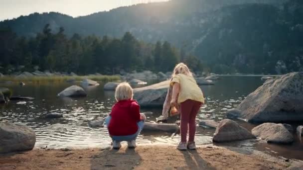 Dos Niños Juegan Con Agua Orilla Del Lago Montaña Atardecer — Vídeos de Stock
