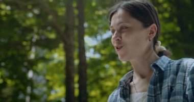 Doğadaki güzel mutlu kadın portresi birileriyle konuş ve gülümse. Ağaçların doğal yeşil arka planında bir kadın. 