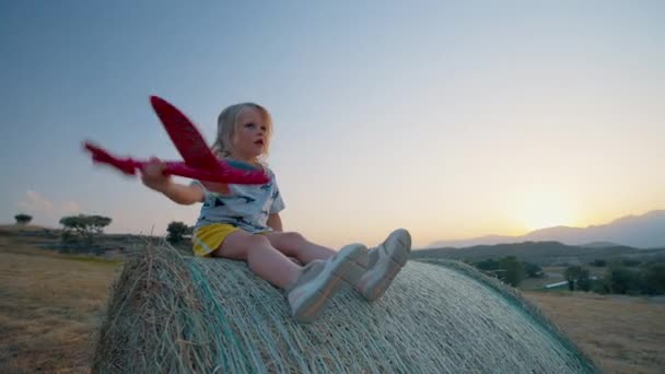 Menina Brincar Com Brinquedo Avião Sentado Fardo Feno Campo Viagem — Vídeo de Stock