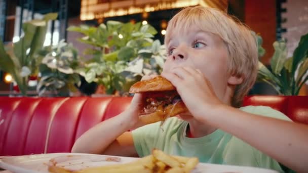 Niezdrowe Jedzenie Fast Foodzie Mały Chłopiec Gryzie Hamburgera Oddzielną Cebulę — Wideo stockowe