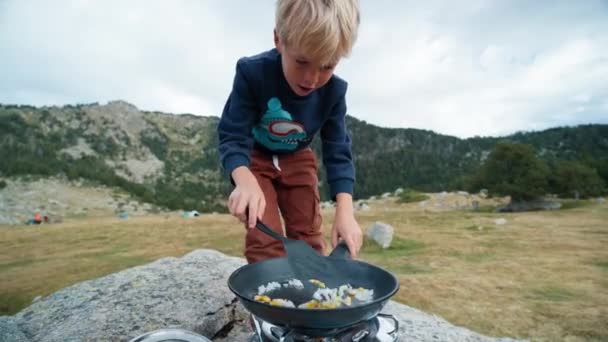 孩子们在假期旅行时帮助妈妈在户外做饭 小男孩露营时把蔬菜放在油锅里 烤玉米和洋葱当煎蛋卷 — 图库视频影像
