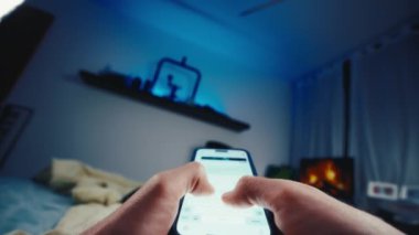 Geceleri yatakta uzanan bir adam cep telefoncusu perspektifinden çekim yapıyor. Sosyal medya kullanarak akıllı telefon dokunmatik klavye üzerinde yazan Pov geniş çekim kişi. 