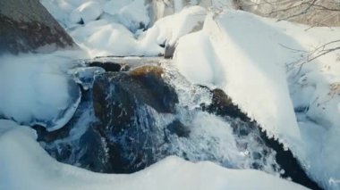 Bahar mevsiminde eriyen kar. Güneşli bir günde dağdaki nehirde kar ve buzun içinden akan su.. 