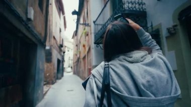 Genç bir kız öğrenci dizüstü bilgisayarını tutarak şehirde yürüyor ve akıllı telefondan fotoğraf çekiyor. Avrupa 'da turistler gezer ve keşfederler. Memnun genç bayan tatilde..