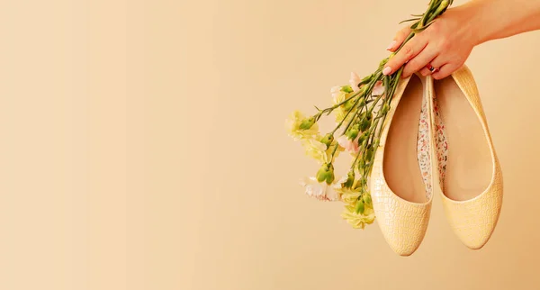 Spring shoes banner background. Fashion - footwear for woman. Pastel yellow ballet flats (ballerinas) and flowers on beige. Free copy (text) space.
