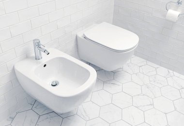 Modern banyo. Duvar asılmış tuvalet ve bide. İç tasarım - farklı şekillerde beyaz seramik fayanslar.