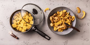 Cooking - preparing boiled potatoes. Pot and bowl with potato peels - kitchen worktop captured from above (top view, flat lay).