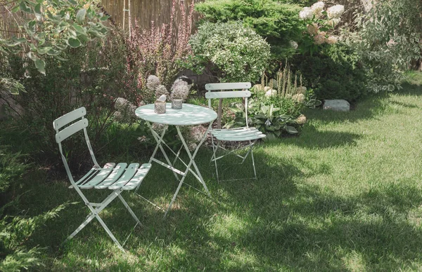 美丽的 绿色的 舒适的花园角落 有一个油腻的薄荷桌 椅子和白色的水仙花 园艺和景观设计 法国风格 浪漫休闲的角落 图库图片