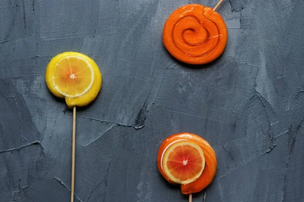 オレンジとレモンのロリポップがグレーの背景に — ストック写真