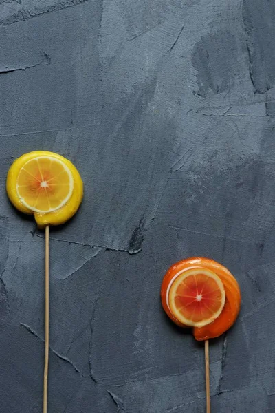 灰色背景上的橙子和柠檬棒棒糖 — 图库照片