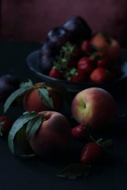Şeftali, erik ve çilek siyah arka planda