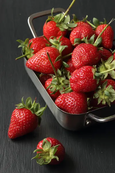 黑色背景的草莓 金属碗里的草莓 免版税图库照片