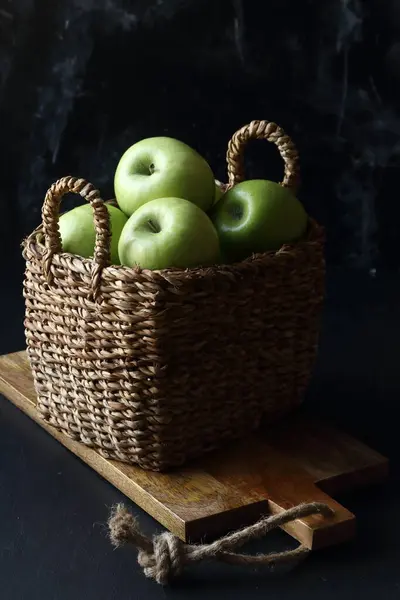 黑色底色的篮子里的绿色苹果 图库图片