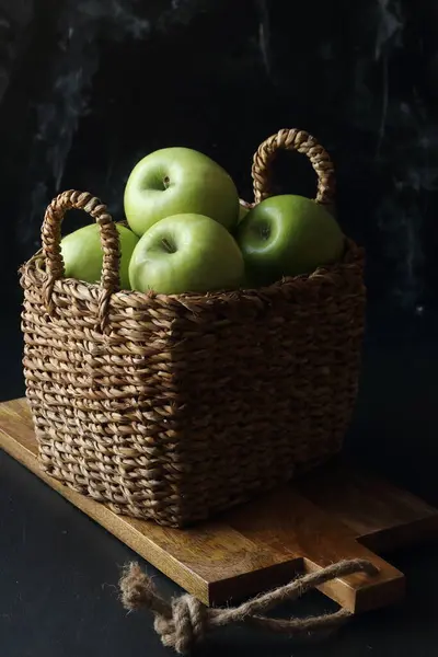 黑色底色的篮子里的绿色苹果 免版税图库图片
