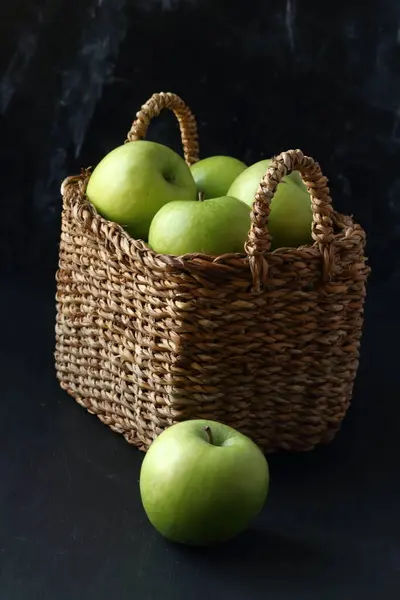 黑色底色的篮子里的绿色苹果 免版税图库图片