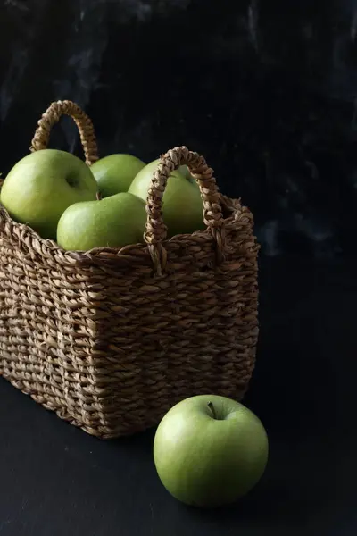 黑色底色的篮子里的绿色苹果 图库照片