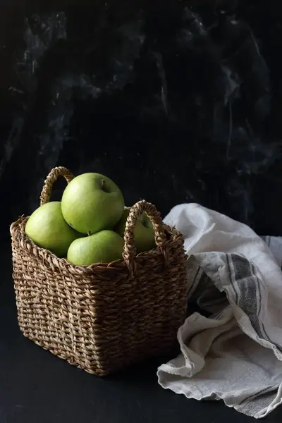 黑色底色的篮子里的绿色苹果 图库图片