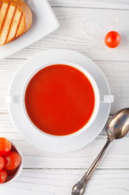Fresh tomato soup in a white bowl on a wooden background. View from above. copy space