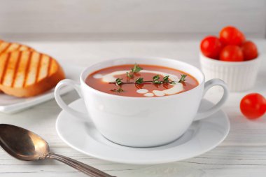 Fresh tomato soup in a white bowl on a wooden background. Side view. copy space