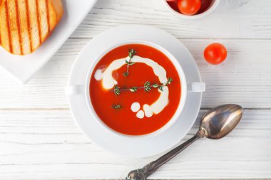 Fresh tomato soup in a white bowl on a wooden background. View from above. copy space