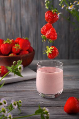 Kahvaltı için sağlıklı yemek. Gri ahşap arka planda bir kavanozda çilekli smoothie ya da milkshake.