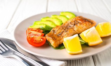 Avokado, limon, otlar ve domatesli kızarmış balık.
