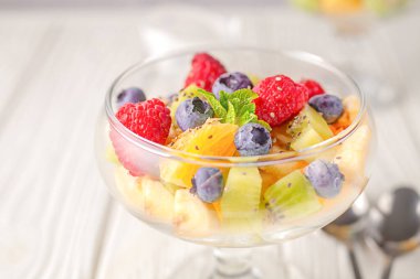 Hafif ahşap bir masa arkasında nefis diyet taze meyve salatası.