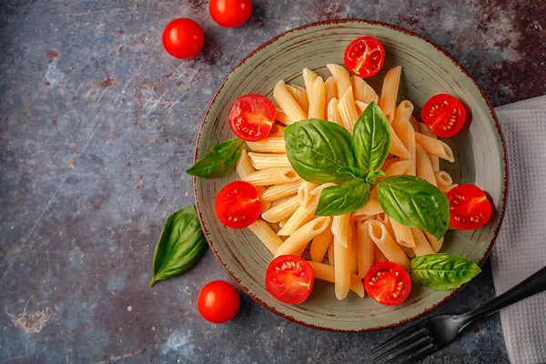 stock image Delicious pasta with aromatic basil and tomatoes close-up on a dish. Top view.