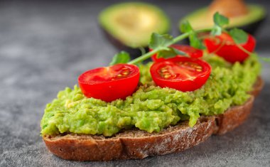 Avokado ve domatesli vejetaryen sandviç, gri arka planda. Diyet yemek..