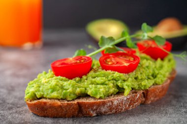 Avokado ve domatesli vejetaryen sandviç, gri arka planda. Diyet yemek..