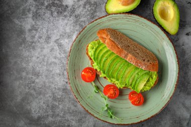 Avokado ve domatesli vejetaryen sandviç, gri arka planda. Diyet yemek..