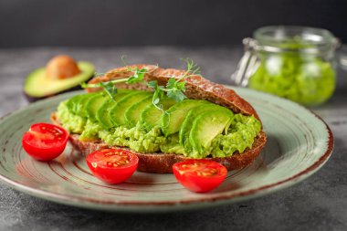 Avokado ve domatesli vejetaryen sandviç, gri arka planda. Diyet yemek..