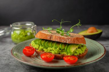 Avokado ve domatesli vejetaryen sandviç, gri arka planda. Diyet yemek..