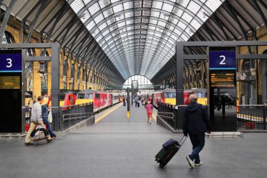 Londra 'daki King' s Cross Tren İstasyonu, Londra 'daki King' s Cross tren istasyonunun canlı bir görüntüsü, sembolik cam çatısını ve işlek platformlarını sergiliyor. Bagajlı gezginler varış yerlerine doğru yürür..