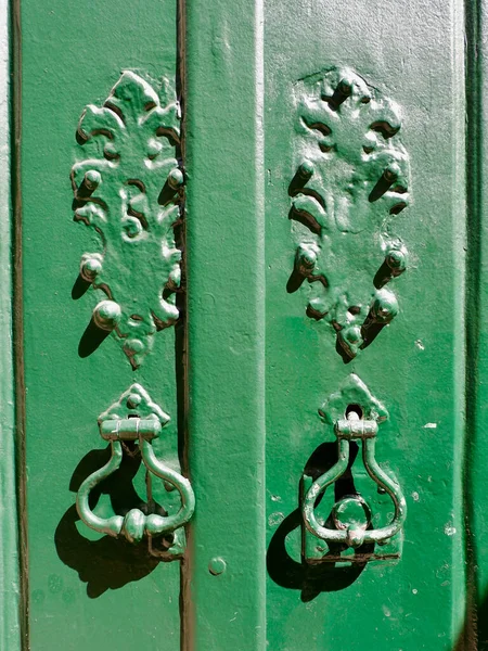 Old vintage furniture on green painted door in Lisbon, Portugal.