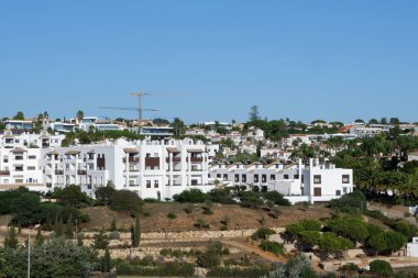 Holiday houses of white colour in the summer resort in Algarve, Portugal. Panoramic view from far.