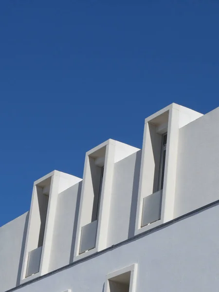 Minimal lines of modern white building against saturated blue sky. Lined minimalistic architecture. Vertical photo.