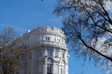 Baharın başlarında İspanya 'nın başkenti Madrid' in Chamberi semtinde ağaçsız ağaçların arasından görülen yuvarlak klasik bina..