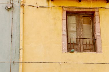 Bosa, Sardinya, İtalya 'da terk edilmiş evin yıpranmış duvarında kırık camlar olan eski püskü bir pencere..