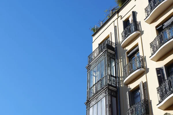 Madrid, İspanya 'nın merkezindeki antik bir binanın köşesinde şık klasik balkonlar parlatılmış ve açılmış. Bej bina duvarında metalik kıvrımlı siyah balkon