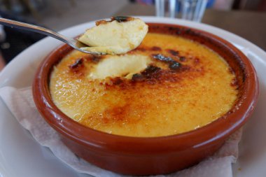 Kaşıkla yanmış creme brulee 'ye dalmış. Yaklaş. Geleneksel Fransız çölünde karamel kırmak. Colliure, Fransa 'daki kafede masada krema katalana.