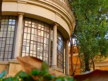 Madrid, İspanya 'nın tarihi bölgesinde bahçe yeşilliği çalılıklarından görülen cam pencereyle kaplı yuvarlak klasik teras..