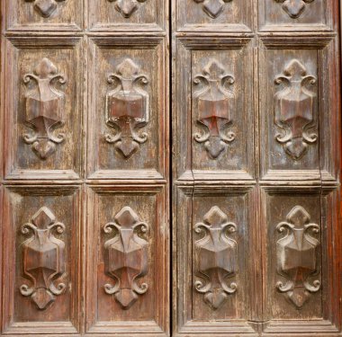 Eski püskü ahşap süslemeler yıpranmış eski kapılarda. Antika zanaatkârının ayrıntıları ahşap yüzeyi tırmaladı. İtalyan mimarisi.