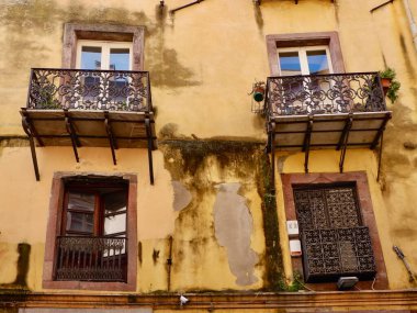 Bosa, İtalya 'nın yoksul semtindeki eski sarı duvarların camları ve balkonları yıpranmış. Klasik İtalyan mimarisi..