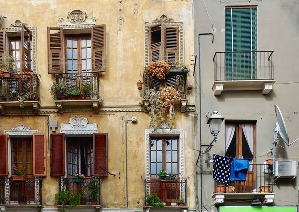 Old-fashioned authentic facades with worn shuttered windows and balconies in Cagliari, Sardinia, Italy. Vintage old Italian architecture.