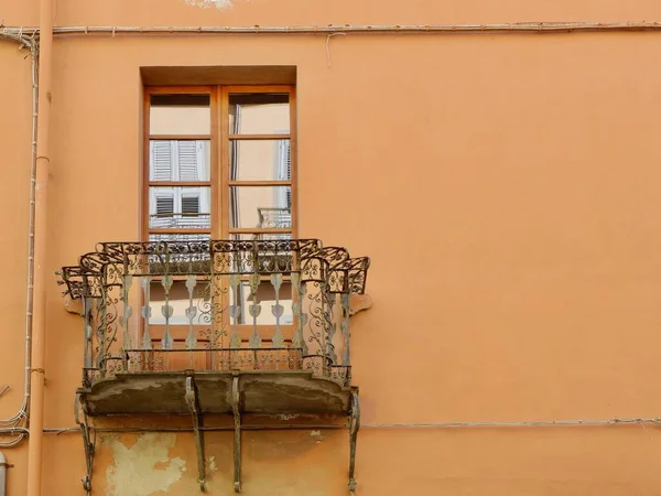 Antika metalik balkon ve eskimiş eski kablolarla birlikte solmuş koyu bej bir duvarın penceresi. İtalya, Cagliari 'de eski İtalyan mimarisi.