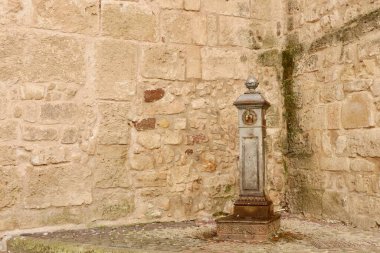 İtalyan çeşmesi caddenin köşesinde Alghero, Sardinya, İtalya 'nın eski taş duvarına karşı. Yıpranmış içme musluğu. Klasik İtalyan mimarisi.