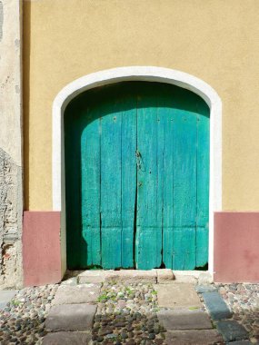 Alghero, Sardinya, İtalya sokaklarında boyanmış duvardaki eski ahırın ahşap kapısını kapat. Klasik İtalyan mimarisi.